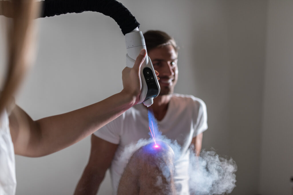 Eine Person erhält eine Laserbehandlung am Knie, während sie lächelt.