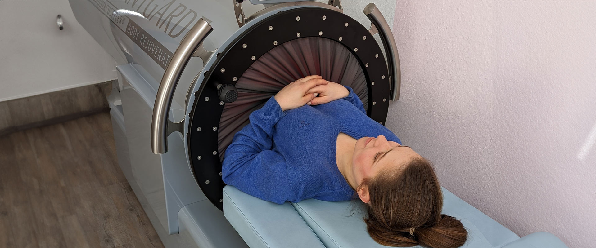 Person liegt entspannt in blauem Pullover in einem medizinischen Gerät mit futuristischem Design.